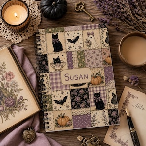 Puede incluir: Un cuaderno de espiral con un diseño de patchwork de gatos negros, murciélagos, fantasmas y calabazas en tonos apagados de morado, verde y crema. Una etiqueta rectangular central muestra el nombre Susan en una fuente serif marrón.