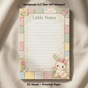 May include: A 12.7 x 17.8 cm tear-off notepad with a patchwork border design. The notepad features the text "Little Notes" and a bunny illustration with a pink bow. It contains 50 sheets of premium paper.