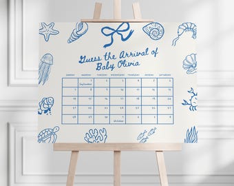 Könnte beinhalten: Ein weißes Schild auf einer hölzernen Staffelei mit blauen nautischen Illustrationen und Text. Auf dem Schild steht "Erraten Sie die Ankunft von Baby Olivia" und es enthält einen Kalender mit Daten im September und Oktober. Dekorative Elemente sind Seestern, Muschel und Meerestiere.