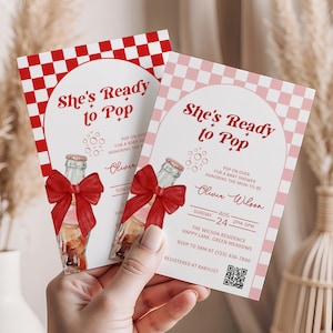 May include: Two baby shower invitations with a red and white checkered pattern. The invitations feature the text "She's Ready to Pop" and a watercolor illustration of a bottle with a red bow. The invitations include event details.