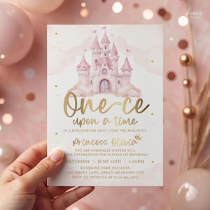 May include: A pink and gold invitation card featuring a fairytale castle illustration. The text reads "One upon a time" and invites guests to a princess's first birthday party. The card is held by a hand.