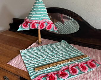 May include: A handmade Christmas tree and placemat in turquoise, white, and red. The tree is conical, and the placemat has a decorative border. A wooden ruler on the placemat reads "Do Unto Others As You Would Have Them Do Unto You."