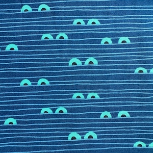 Könnte beinhalten: Ein Stoff mit einem sich wiederholenden Muster aus stilisierten Augen. Die Augen sind helltürkis mit schwarzen Pupillen, vor einem Hintergrund aus horizontalen blauen und weißen Streifen. Der Gesamteffekt ist ein verspieltes, skurriles Design.