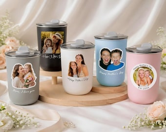 May include: A collection of insulated tumblers in various colors, each adorned with a photo and text. The tumblers include gray, black, white, light blue, and pink. The text includes "Happy Mother's Day" and "Mom, I love you."