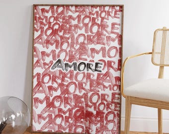 May include: A framed art print with the word "AMORE" in a mix of red and silver lettering. The background is filled with the word "MORE" in red, creating a layered effect. The frame is a warm brown color.
