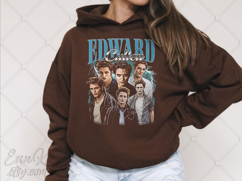 May include: A brown hooded sweatshirt featuring a graphic of Edward Cullen from the Twilight series. The design includes the name "EDWARD Cullen" in blue text with images of the character. The sweatshirt is a solid brown color.