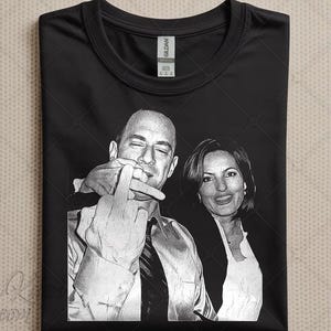 May include: Black t-shirt with a grayscale image of two people. One is making a rude hand gesture, the other is smiling. The shirt has a crew neck and a tag.