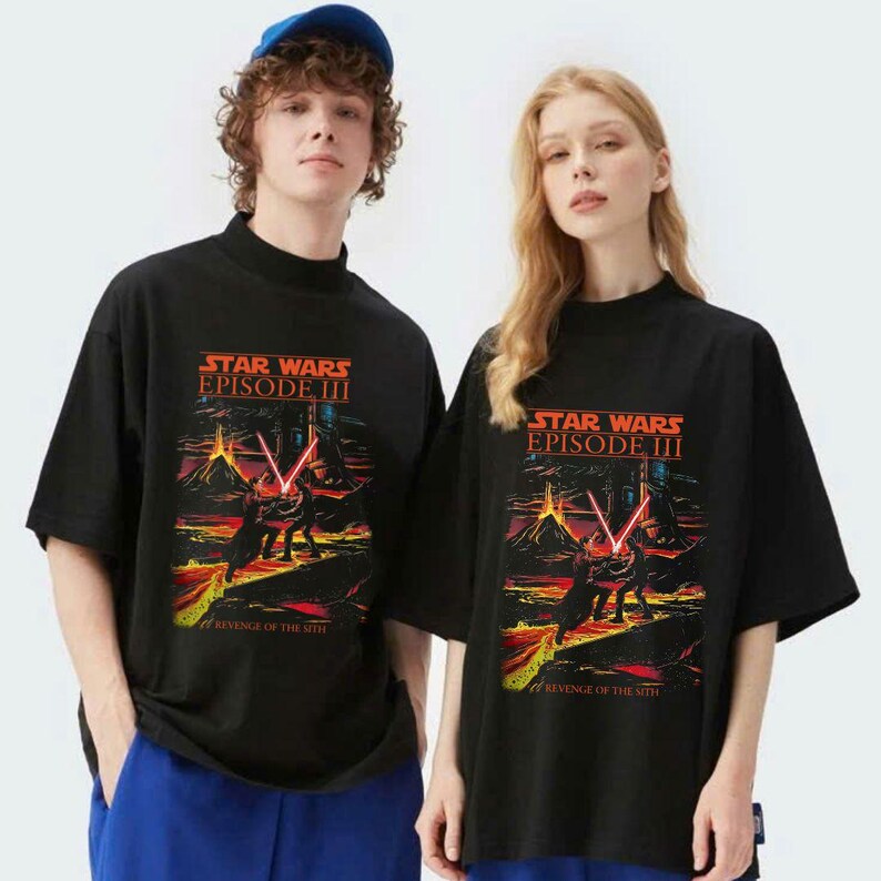 May include: Black t-shirts featuring a Star Wars Episode III graphic with a scene of a lightsaber battle. The text "STAR WARS EPISODE III REVENGE OF THE SITH" is displayed in orange and yellow. The shirts have a mock neck and short sleeves.