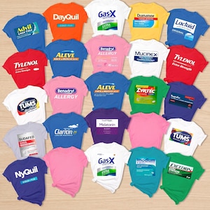 Op de afbeelding: Een collectie van vijfentwintig t-shirts in diverse effen kleuren, elk voorzien van een ander opgedrukt logo van veelvoorkomende vrij verkrijgbare medicijnen, waaronder Advil, DayQuil, Gas-X, Dramamine, Lactaid, Tylenol, Aleve, Benadryl, Mucinex, Zyrtec, Tums, Sudafed, Claritin, Natrol en Excedrin.