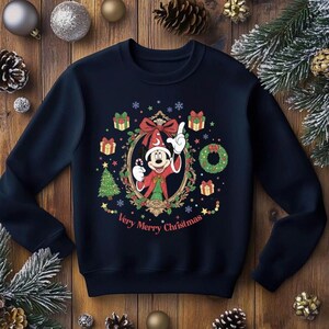 以下が含まれることがあります： ネイビーブルーのクリスマススウェットシャツ。ミッキーマウスが祝祭衣装で描かれています。ギフトボックス、クリスマスツリー、そして「Very Merry Christmas」の文字がデザインに含まれています。