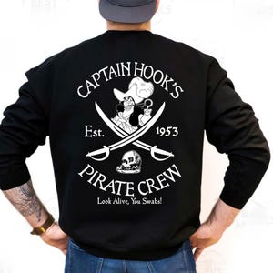 May include: Black sweatshirt featuring a Captain Hook's Pirate Crew design. The graphic includes an illustration of Captain Hook, crossed swords, a skull, and the text "Look Alive, You Swabs!" The design is in white.