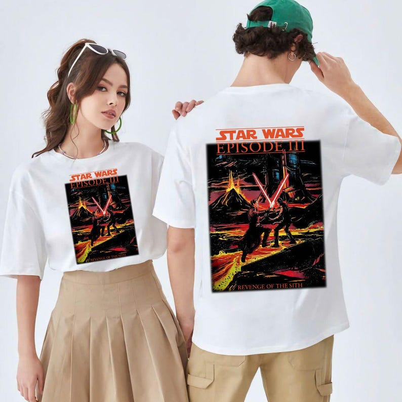 May include: White t-shirts featuring a Star Wars Episode III graphic. The front and back of the shirts display a colorful scene with lightsabers and the text "REVENGE OF THE SITH".