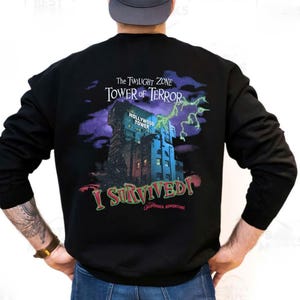May include: Black sweatshirt with a graphic of the Hollywood Tower Hotel from The Twilight Zone Tower of Terror. The design includes the text "The Twilight Zone Tower of Terror" and "I Survived! California Adventure".