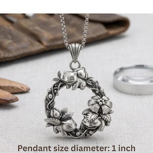 May include: Silver-toned pendant necklace featuring a circular design with three Bulbasaur figures and floral accents. The pendant is 1 inch in diameter and hangs from a delicate chain. The text at the bottom reads: Pendant size diameter: 1 inch.