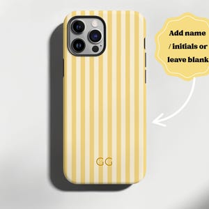 Puede incluir: Funda de teléfono a rayas amarillas y blancas con un recorte para la cámara. La funda tiene las iniciales "GG" en la parte inferior. La imagen incluye una forma amarilla con el texto "Añadir nombre / iniciales o dejar en blanco".