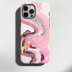 Könnte beinhalten: Weißes iPhone-Case mit farbenfrohem, abstraktem Design. Das Design zeigt fließende Pinselstriche in Rosa, Braun und Weiß, mit einem gelb-orangenen Blitz-Akzent. Das Case hat eine glänzende Oberfläche.