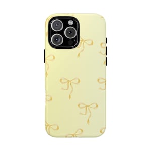 May include: A light yellow phone case with a repeating pattern of watercolor bows in a soft, muted gold color. The case has a glossy finish and a camera cutout for a multi-lens system.