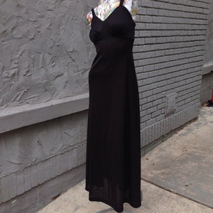 Puede incluir: Un vestido maxi negro con un diseño sencillo y sin mangas. El vestido tiene un corpiño ajustado y una falda fluida.