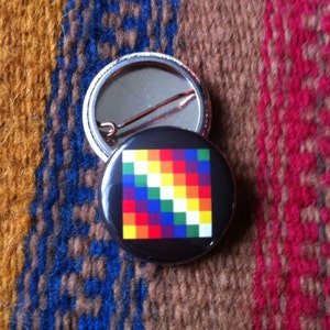 May include: A colourful button with a rainbow pattern. The button is round and has a metal pin on the back.