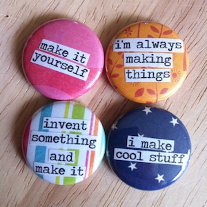 May include: Four colorful round buttons with inspirational messages. The buttons are printed with the following text: "make it yourself", "i'm always making things", "invent something and make it", and "i make cool stuff".