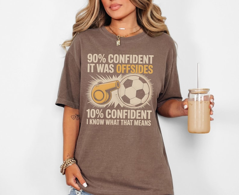 May include: Brown t-shirt with the text "90% CONFIDENT IT WAS OFFSIDES 10% CONFIDENT I KNOW WHAT THAT MEANS." The graphic includes a soccer ball and a referee whistle.
