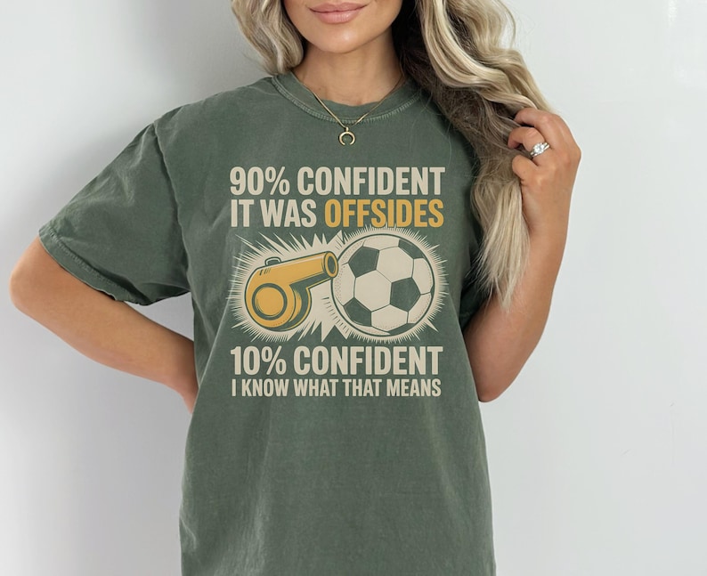 May include: Olive green t-shirt with a soccer-themed graphic. The design features a soccer ball, a referee whistle, and text that reads "90% CONFIDENT IT WAS OFFSIDES 10% CONFIDENT I KNOW WHAT THAT MEANS."