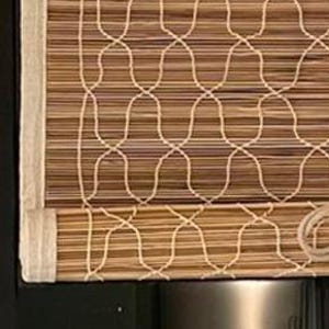 May include: A bamboo roll-up window shade featuring a natural brown horizontal slat design overlaid with a white woven cord pattern. The shade is framed by a light beige fabric border and includes a central pull cord mechanism for adjustment.