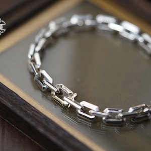 Może przedstawiać: Srebrna bransoletka z łańcuszkiem typu box. Bransoletka wykonana jest z połączonych ze sobą prostokątnych ogniw.