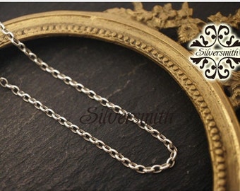 Puede incluir: Un collar de cadena de plata sobre un fondo dorado. La cadena es de estilo simple, con eslabones ovalados. El fondo es un marco decorativo y ornamentado con la palabra "Silversmith" en una fuente estilizada.
