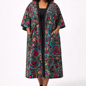 May include: A long, open-front kimono-style robe with a vibrant, colorful pattern. The robe features a black background with a repeating design of red, yellow, and teal shapes. It has a black trim and pockets.