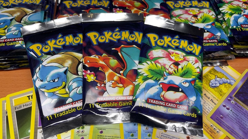 May include: Several Pok&eacute;mon Trading Card Game booster packs with various Pok&eacute;mon characters on the front. The packs are sealed and feature the Pok&eacute;mon logo. Some individual cards are visible in the foreground.