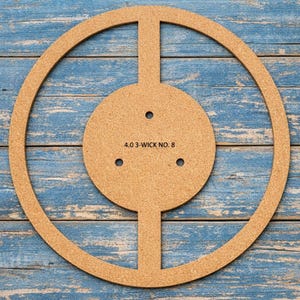May include: A round, cork candle-making template with a central circle and three wick holes. The text "4.0 3-WICK NO. 8" is printed on the central circle. The template is set against a blue wooden background.