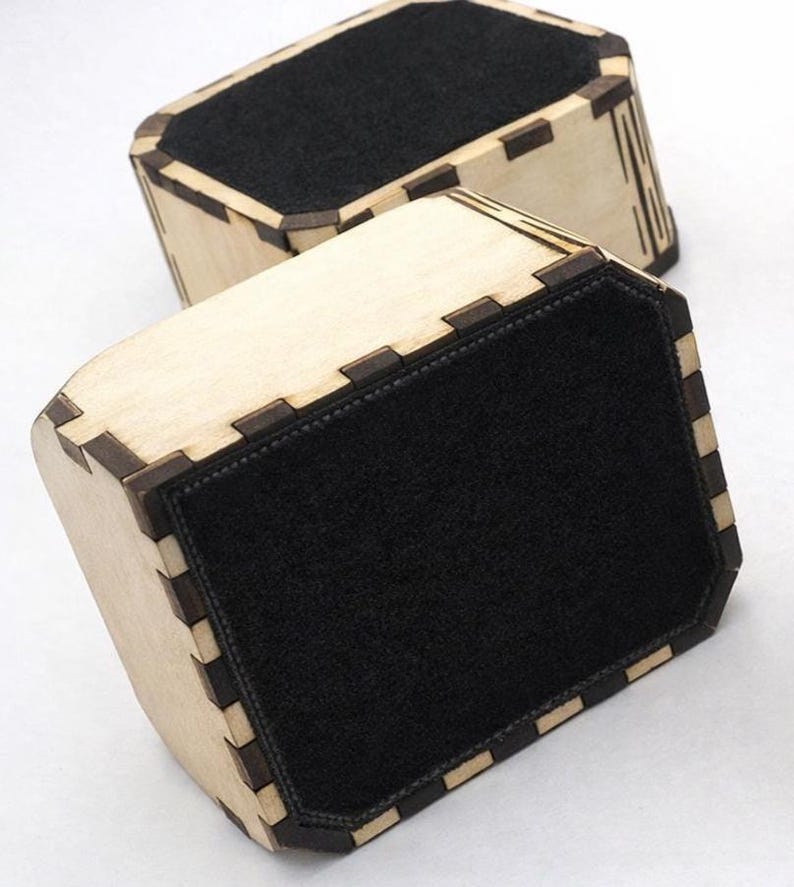 Two handcrafted wooden box bottoms shown flipped over to display their smooth black felt backing. The laser‑cut joints, light natural wood, and precise inset felt highlight the quality and care in the construction. Felt protects surfaces from scratches and adds a polished, finished look to the boxes.