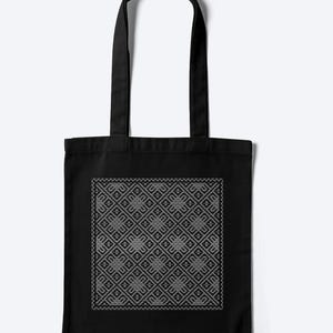 May include: A black tote bag featuring a centred square graphic with a repeating geometric pattern in white. The design consists of interconnected diamond shapes and intricate line work, creating a symmetrical, grid-like visual effect on the fabric.