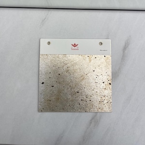 May include: Two metallic silver samples with a speckled pattern. Each sample is attached to a white card with the brand name "TAIHO" and a product code. The samples are displayed on a white surface.