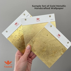 May include: A sample set of gold metallic handcrafted wallpaper. The image shows three gold leaf samples with white header cards. The header cards have the text "Sample Set of Gold Metallic Handcrafted Wallpaper" and the brand logo. The gold leaf samples have different textures.