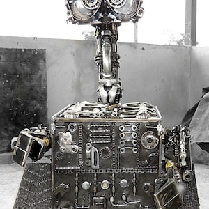 May include: A robot made entirely of metal parts, resembling the character WALL-E from the animated film. The robot is made of gears, chains, and other metal pieces. The robot has a large, square body and a small head with two large, round eyes.