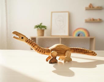 May include: A wooden dinosaur toy with a long neck and tail, standing on a light-colored surface. The toy is made of light brown wood with visible grain and is designed with articulated joints. The background includes a shelf, a framed picture, and a rainbow.