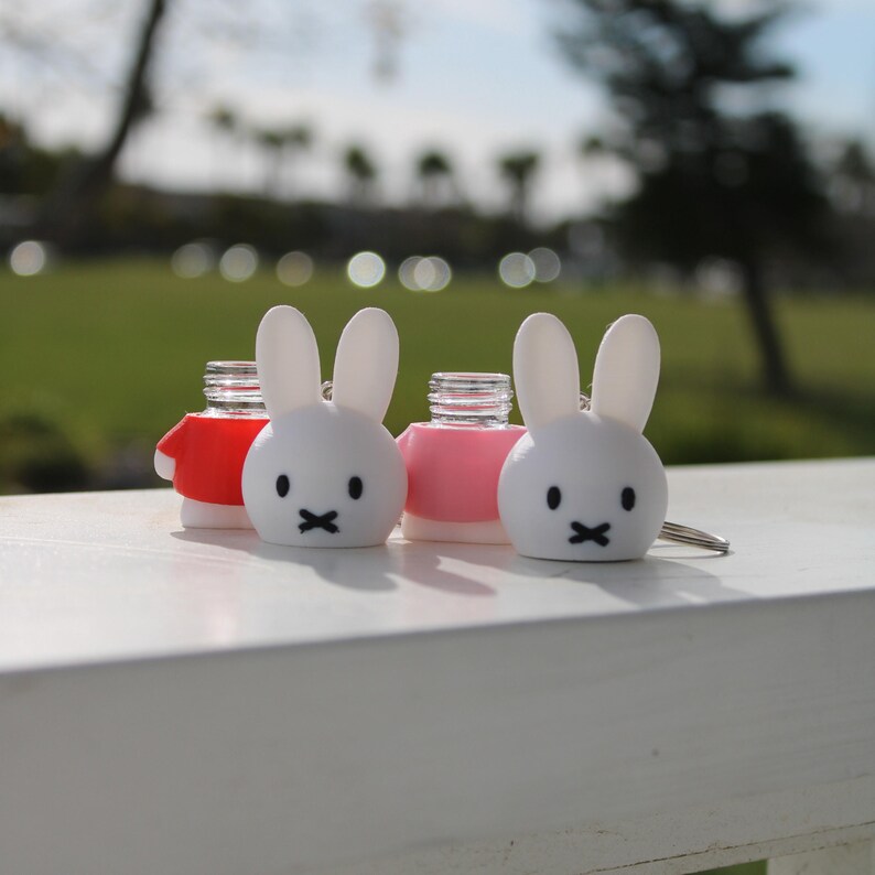 Pode incluir: Tr&ecirc;s rolhas de garrafa de coelho branco com topos vermelhos, rosa e brancos. As rolhas de coelho t&ecirc;m olhos pretos e uma boca preta.