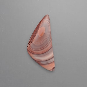 May include: A triangular shaped piece of red, brown, and white banded agate with a swirling pattern.