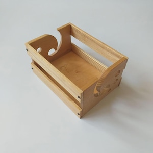 May include: A wooden crate with a cutout design on the side. The crate is made of light brown wood and has a natural finish.