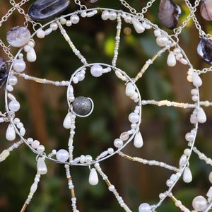 Handmade ocean decor suncatcher displayed against greenery with sunlight reflecting through beads.