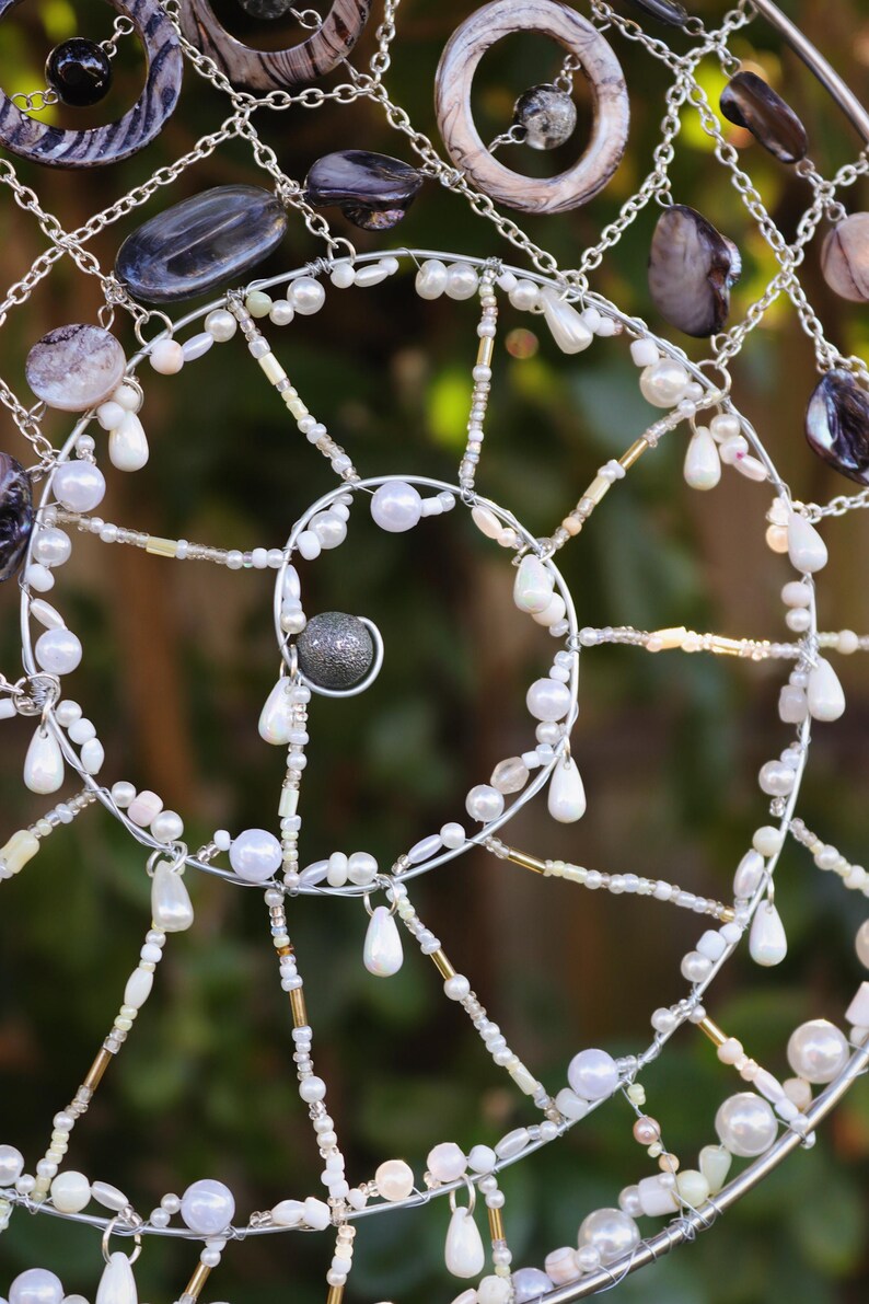 Handmade ocean decor suncatcher displayed against greenery with sunlight reflecting through beads.