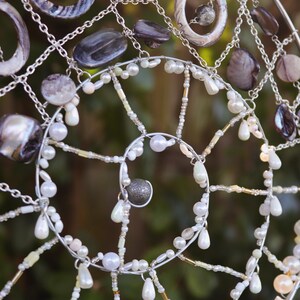 Detail shot of spiral wire structure with shells and pearl accents in coastal fairycore style.