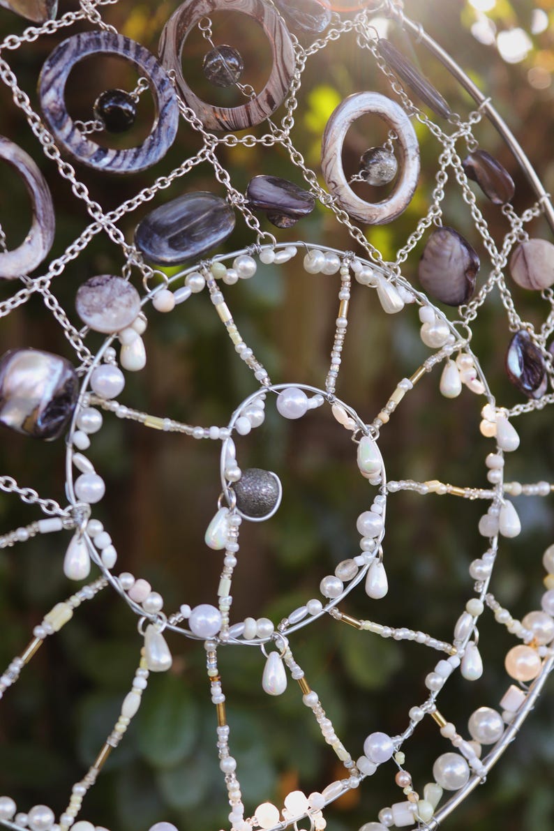Detail shot of spiral wire structure with shells and pearl accents in coastal fairycore style.