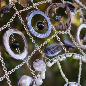 Close up of handmade coastal suncatcher showing freshwater pearls, shell rings and ocean coloured glass beads.