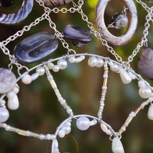 Close up of iridescent beads and pearls reflecting sunlight on spiral suncatcher.