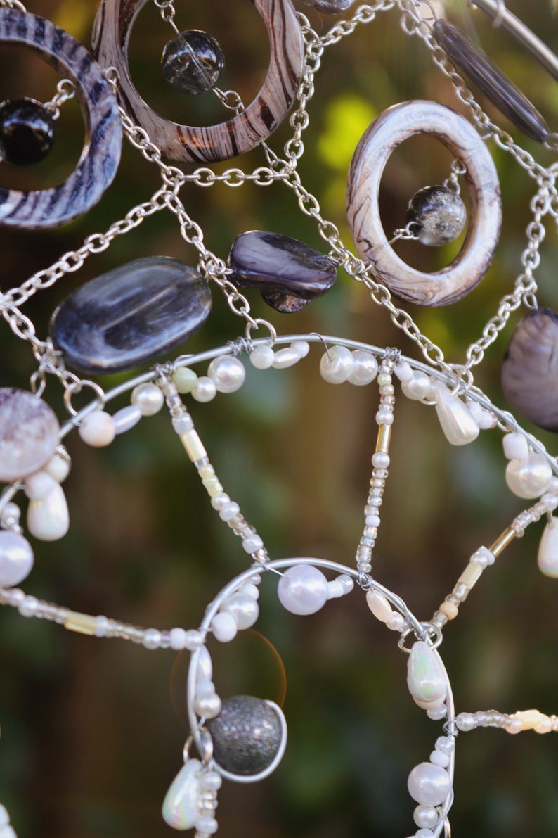Close up of iridescent beads and pearls reflecting sunlight on spiral suncatcher.