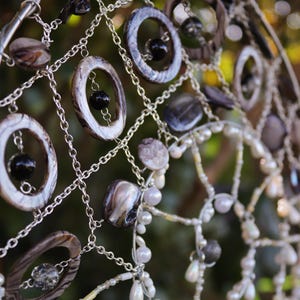Handmade mermaid aesthetic wall hanging with shells and coastal elements ready for display. Mermaid inspired spiral wall hanging with nautical shell details and silver charm centre.