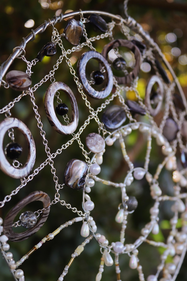 Handmade mermaid aesthetic wall hanging with shells and coastal elements ready for display. Mermaid inspired spiral wall hanging with nautical shell details and silver charm centre.